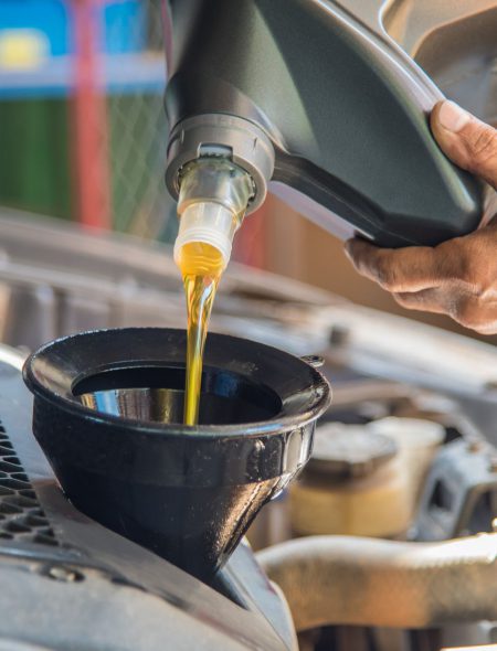 Car maintenance servicing mechanic pouring new oil lubricant into the car engine, A mechanic pours fresh oil into a car engine as part of its maintenance